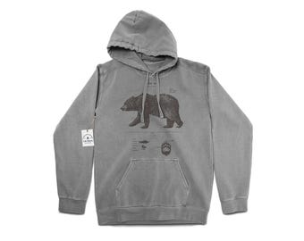 May include: A gray hooded sweatshirt with a vintage look featuring a black and white illustration of a bear with the text "Ursus Arctos" above it. The illustration includes a bear paw print, fish, and other details.