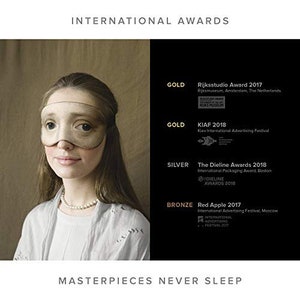 May include: A woman wearing a sleep mask with the text "Masterpieces Never Sleep" below. The image also includes a list of awards the sleep mask has won, including the Rijksstudio Award 2017, KIAF 2018, The Dieline Awards 2018, and Red Apple 2017.