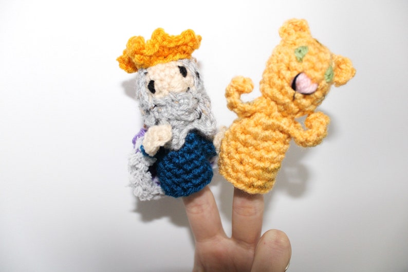 May include: Two finger puppets, one is a king with a yellow crown, gray beard, and blue and gray robe, the other is a yellow bear with green eyes and a pink tongue.