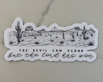 Puede incluir: Pegatina en blanco y negro con un paisaje desértico con cactus y montañas. El texto "THE DEVIL CAN SCRAP BUT THE LORD HAS WON" está impreso debajo de la imagen.