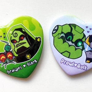 Op de afbeelding: Twee hartvormige knoppen met cartoonfiguren. De eerste knop is groen met een groen en zwart personage met rode ogen en de tekst "Scalpel ♥ Slick". De tweede knop is paars met een groen en zwart personage met groene ogen en een zwart personage met gele accenten en de tekst "Prowl ♥ Bulk".
