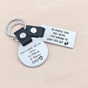 May include: Two silver keyrings with black leather straps. One keyring is round and engraved with "You're stuck with me, Sorry, No Refunds Or Returns". The other is rectangular and says "No matter how big I grow, I will always be your little girl".