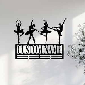 May include: Black metal wall decor featuring five ballerina silhouettes with a personalized nameplate that reads "CUSTOM NAME".