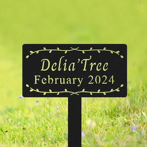 May include: Black metal garden sign with a vine border. The sign reads "Delia'Tree February 2024".