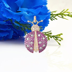May include: A gold-tone pendant charm in the shape of a ladybug with pink and white cubic zirconia stones.