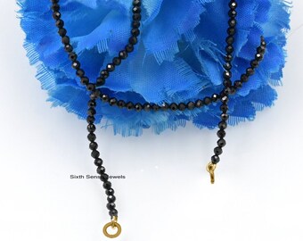 May include: A black beaded necklace with gold clasps. The necklace is made of small, round beads and is approximately 18 inches long.