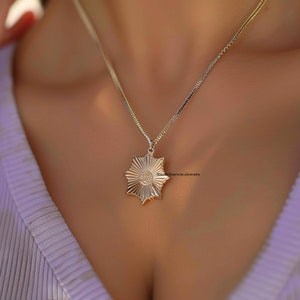 以下が含まれることがあります： 星型のペンダントが付いたゴールドチェーンネックレス。ペンダントはテクスチャ加工された表面と中央に小さな円があります。