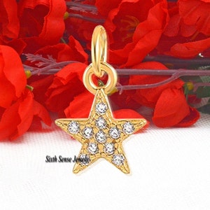 May include: A gold-tone star charm with clear rhinestones. The charm is perfect for adding a touch of sparkle to jewelry or crafts.