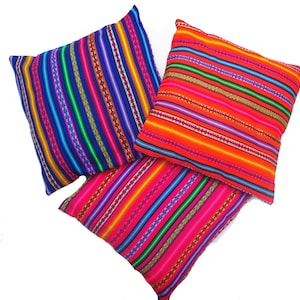 May include: Three colorful striped throw pillows with a bright orange, pink, and blue color scheme. The pillows are made of a soft, woven fabric and have a traditional design.