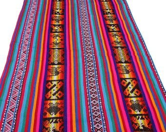 May include: A rectangular table runner featuring a vibrant multi-colored striped pattern in shades of red, orange, yellow, blue, and purple. The fabric includes two wide black bands decorated with repeating geometric and bird-like motifs.