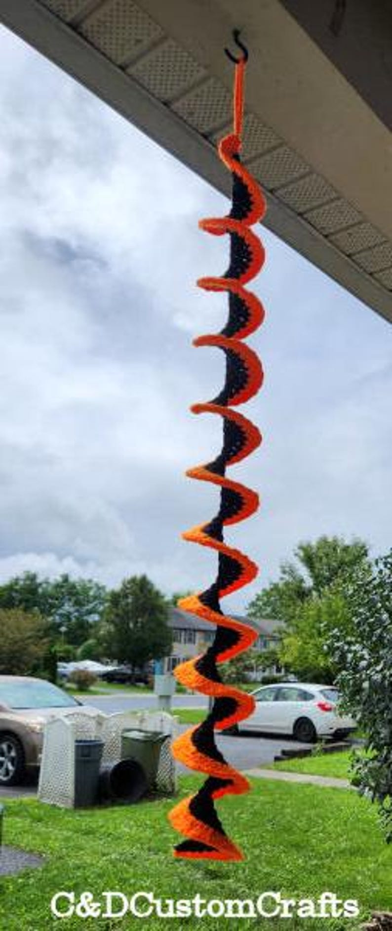 Pu&ograve; includere: Una decorazione a spirale in crochet nero e arancione. La spirale &egrave; realizzata in filato ed &egrave; appesa a un gancio. La spirale &egrave; lunga circa 90 cm.