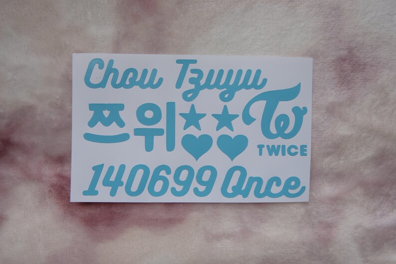 May include: A white sticker sheet with light blue text and graphics. The text includes the name "Chou TzuYu", Korean characters, stars, hearts, the word "TWICE", and the numbers "140699 Once".