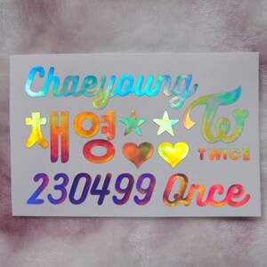 May include: Holographic sticker with the name "Chaeyoung" in a script font, along with Korean characters and the word "TWICE". Includes stars, hearts, and the word "Once". The sticker has a rainbow iridescent finish.