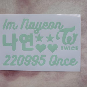 May include: A white sticker with mint green text. The text includes "Im Nayeon", Korean characters, stars, hearts, the word "TWICE", the numbers "220995", and the word "Once".