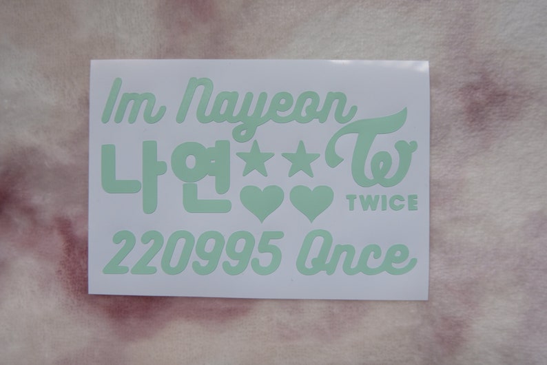May include: A white sticker with mint green text. The text includes "Im Nayeon", Korean characters, stars, hearts, the word "TWICE", the numbers "220995", and the word "Once".