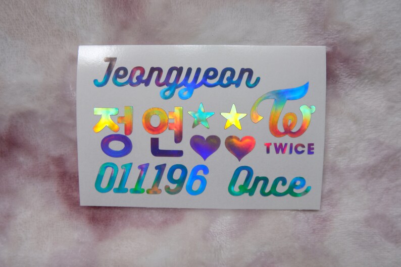 May include: A holographic sticker featuring the name "Jeongyeon" in a stylized font, along with Korean characters, stars, hearts, and the word "TWICE". The sticker also includes the numbers "011196" and the word "Once".
