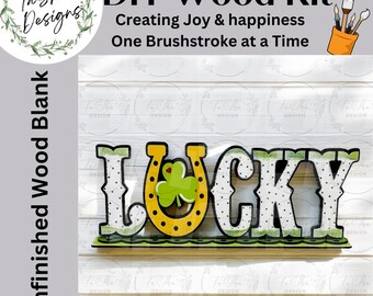 May include: A DIY wood kit featuring the word LUCKY in cutout letters. The letter U is replaced by a yellow horseshoe with a green shamrock. The letters have a white and green polka dot pattern. Text reads DIY Wood Kit, Creating Joy & happiness One Brushstroke at a Time, and Unfinished Wood Blank.