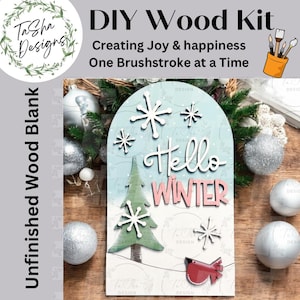 May include: A DIY wood kit with a winter theme. The kit includes an unfinished wood blank with the words "Hello Winter" and a Christmas tree design. The kit also includes snowflakes and a red bird. The kit is designed for creating joy and happiness.