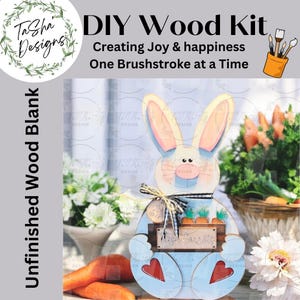 May include: Unfinished wooden bunny rabbit cutout with blue and white paint, holding a basket of carrots. The bunny has pink ears and a white face with black eyes. The basket is labeled "Fresh Carrots".