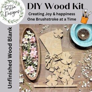 May include: A DIY wood kit with unfinished wood blanks. The kit includes various wooden cutouts, including shamrocks and a decorative piece. The image also shows a wooden bowl with flowers and a small bird's nest.