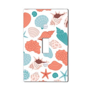 May include: A light switch cover with a seashell pattern. The cover features a variety of seashells in shades of pink, blue, and white on a white background.