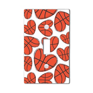 May include: A white light switch cover with a pattern of orange basketballs shaped like hearts.