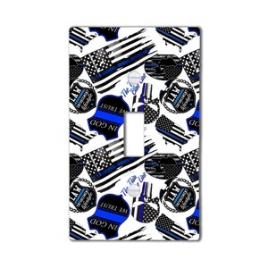 May include: A white light switch cover with a repeating pattern of blue and black American flag designs, police badges, and the text "LAW ENFORCEMENT lifestyle" and "IN GOD WE TRUST".
