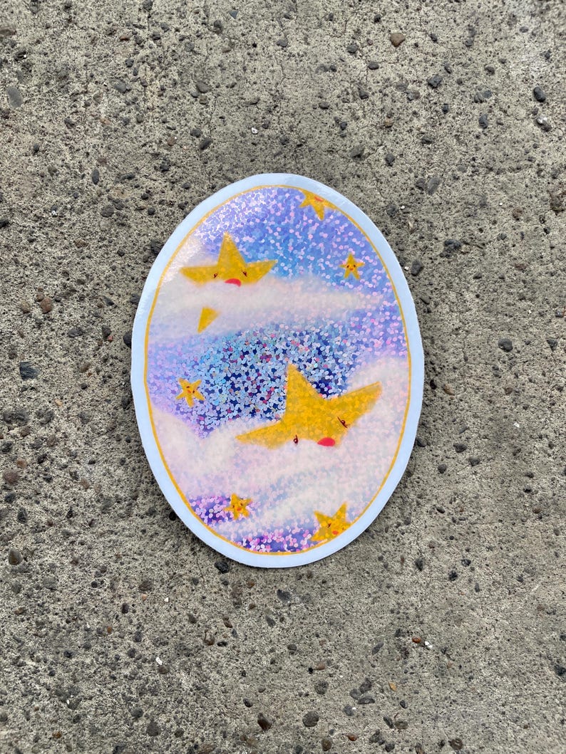 May include: A round sticker with a blue and purple iridescent background. The sticker features three yellow stars with faces, two of which are partially obscured by white clouds. The stars are surrounded by smaller yellow stars.