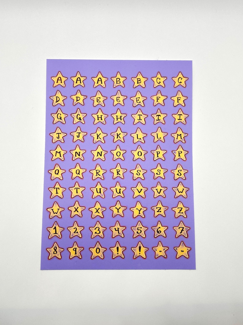 May include: A sheet of purple star-shaped stickers with yellow borders. Each star contains a letter of the alphabet or a number, from A to Z and 0 to 9, plus exclamation points. The stickers are arranged in a grid pattern.