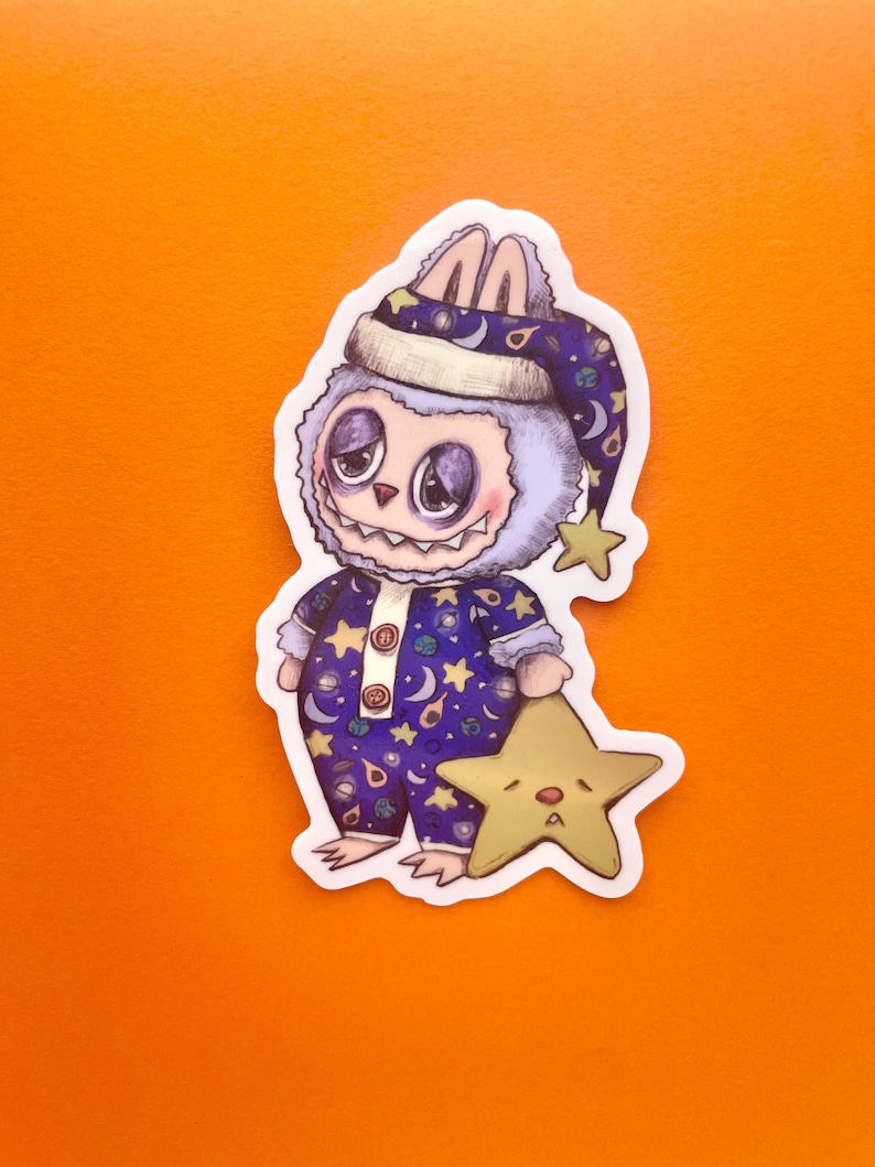 May include: A purple and blue cartoon monster wearing a nightcap and pajamas with stars and moons. The monster is holding a yellow star with a sad face.