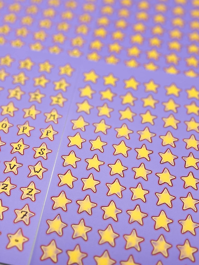 May include: Sheets of purple star stickers with yellow stars and red outlines. Some stickers have letters and numbers. The stickers are arranged in neat rows and columns, creating a visually appealing pattern.