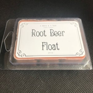 Puede incluir: Un recipiente de cera blanca con una etiqueta que dice "A Wick & A Nod Candle Company Root Beer Float 2.75 oz".