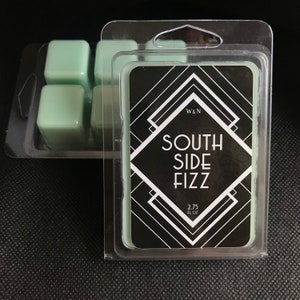 May include: A clear plastic container with four wax melts. The wax melts are a light green color. The container has a label that says "W&N South Side Fizz 2.75 fl oz".