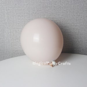 May include: A pale pink balloon with a white knot, sitting on a white surface.