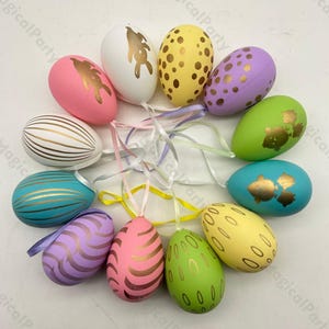May include: Twelve Easter egg decorations with a variety of patterns and colours, including pink, yellow, green, blue, and white. Each egg features a gold design and a ribbon for hanging.