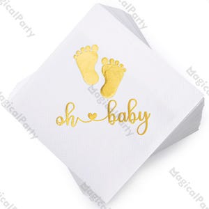 May include: A stack of white paper napkins with gold foil accents. The napkins feature two gold baby footprints and the phrase "oh baby" in gold script, perfect for a baby shower or gender reveal party.