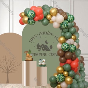 Pode incluir: Um arco de balões verde, marrom e dourado com um padrão de camuflagem. O arco é decorado com uma placa que diz "Fires, Friends, Fun, Camping Crew".