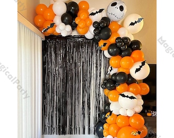 Puede incluir: Un arco de globos con temática de Halloween en naranja, negro y blanco. El arco presenta globos de varios tamaños, incluidos algunos con diseños de murciélagos y Jack Skellington. Una cortina de flecos negra está en el fondo.