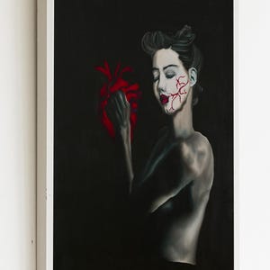 May include: A woman with a red heart in her hand, her face is painted with red veins. The background is black.
