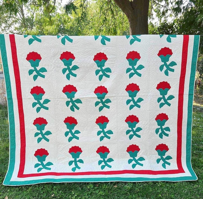 May include: A white quilt with a red and green floral pattern. The quilt has a red and green border.