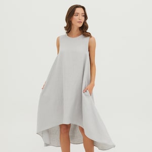 May include: A gray linen dress with a high-low hemline and sleeveless design. The dress has a round neckline and two pockets.