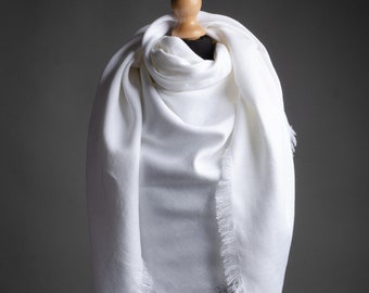 May include: White linen scarf with a fringed edge. The scarf is draped over a mannequin.