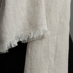 May include: A light beige linen scarf with a fringed edge.