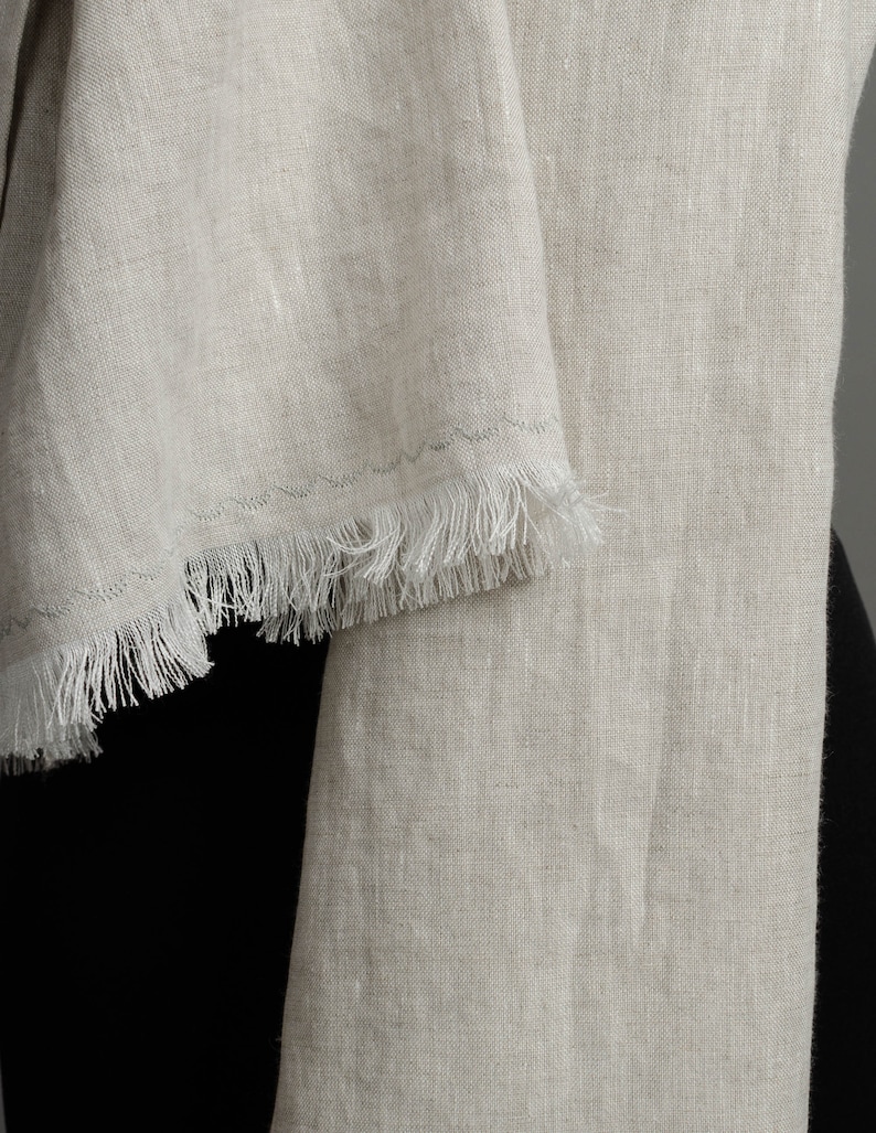 May include: A light beige linen scarf with a fringed edge.
