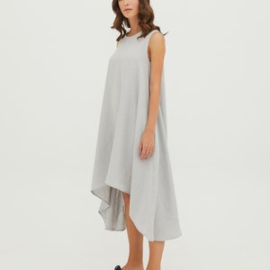 May include: A light gray sleeveless linen dress with a high-low hemline. The dress is loose-fitting and has a relaxed silhouette.