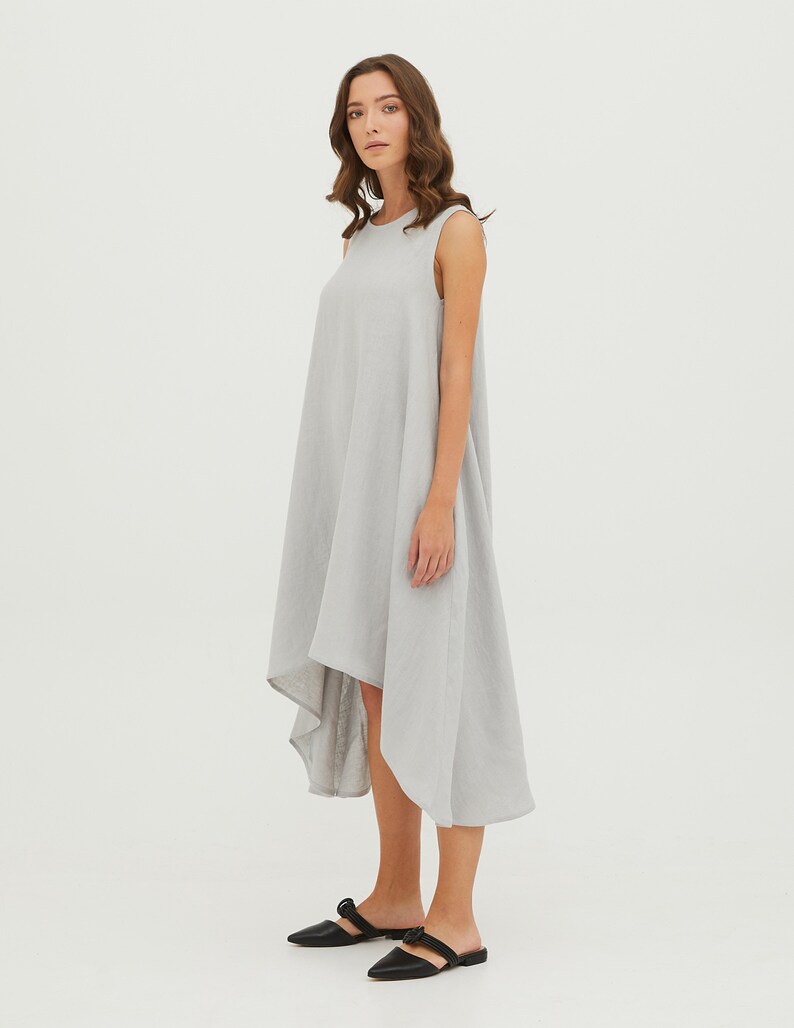 May include: A light gray sleeveless linen dress with a high-low hemline. The dress is loose-fitting and has a relaxed silhouette.