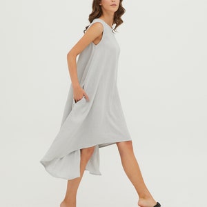 May include: A light gray sleeveless dress with a high-low hemline. The dress has a relaxed fit and is made of a lightweight fabric.