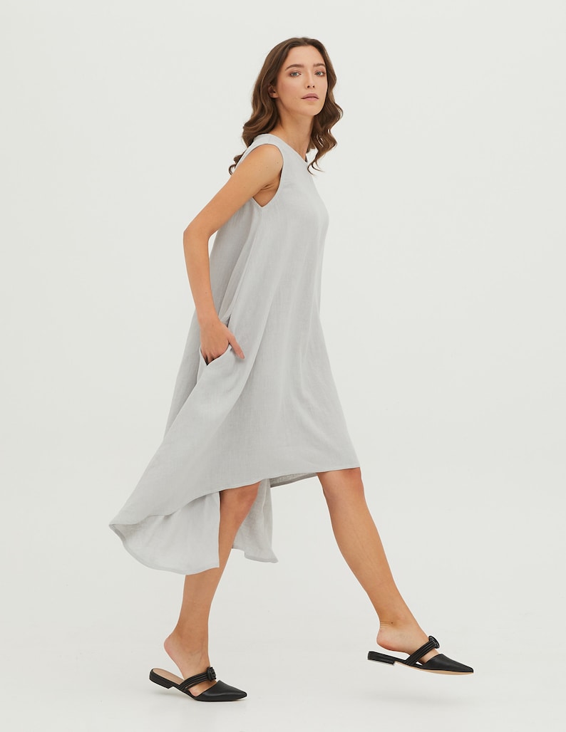 May include: A light gray sleeveless dress with a high-low hemline. The dress has a relaxed fit and is made of a lightweight fabric.