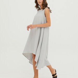May include: A light gray sleeveless linen dress with a high-low hemline. The dress is flowy and has a relaxed fit.