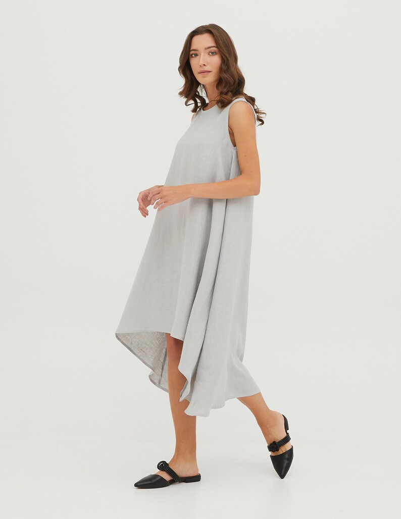 May include: A light gray sleeveless linen dress with a high-low hemline. The dress is flowy and has a relaxed fit.